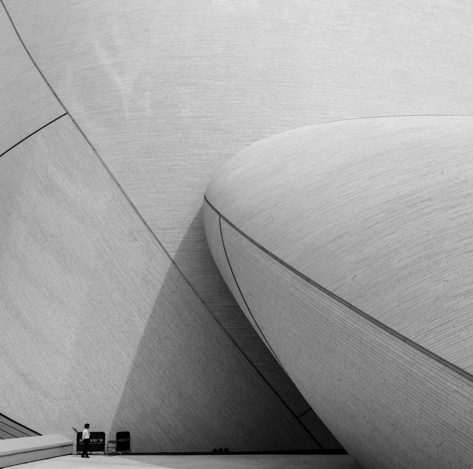 Modern architecture with curved concrete walls and a person