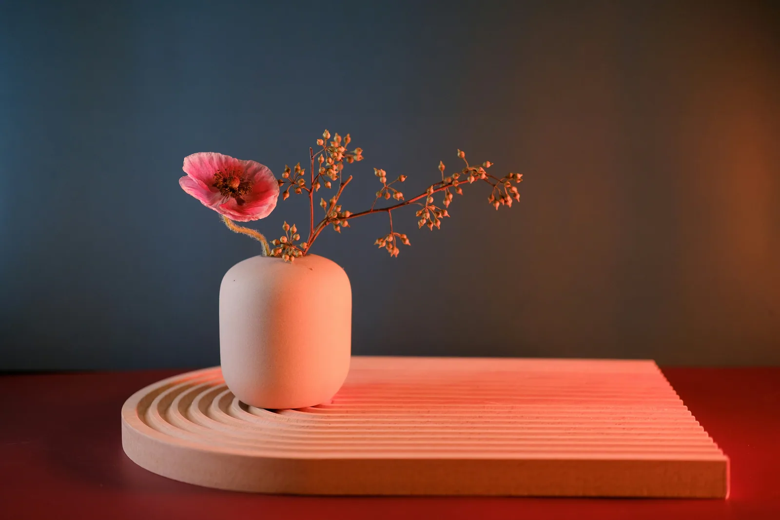 A white vase with a pink flower in it