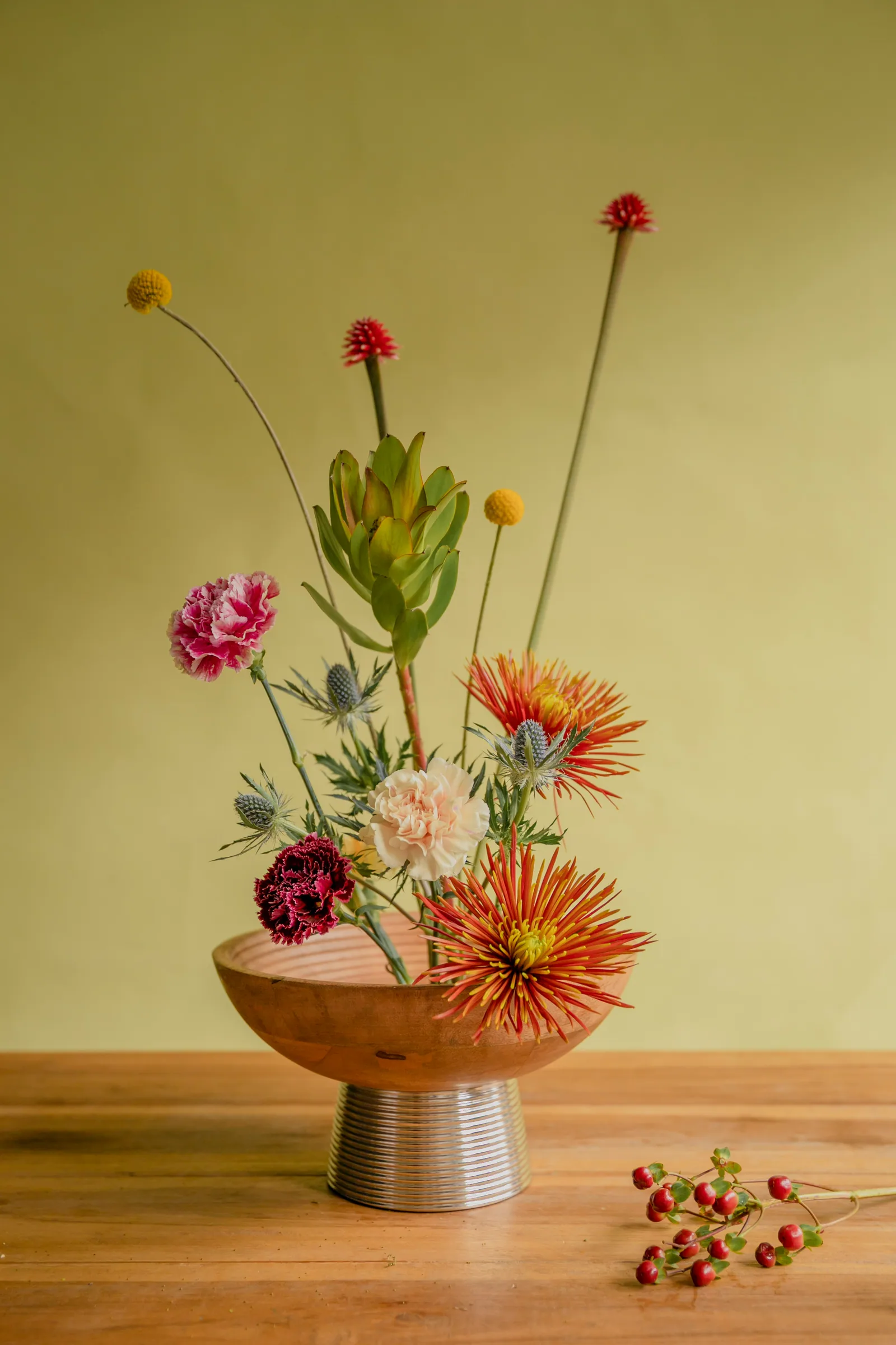 A wooden bowl filled with flowers on top of a wooden table