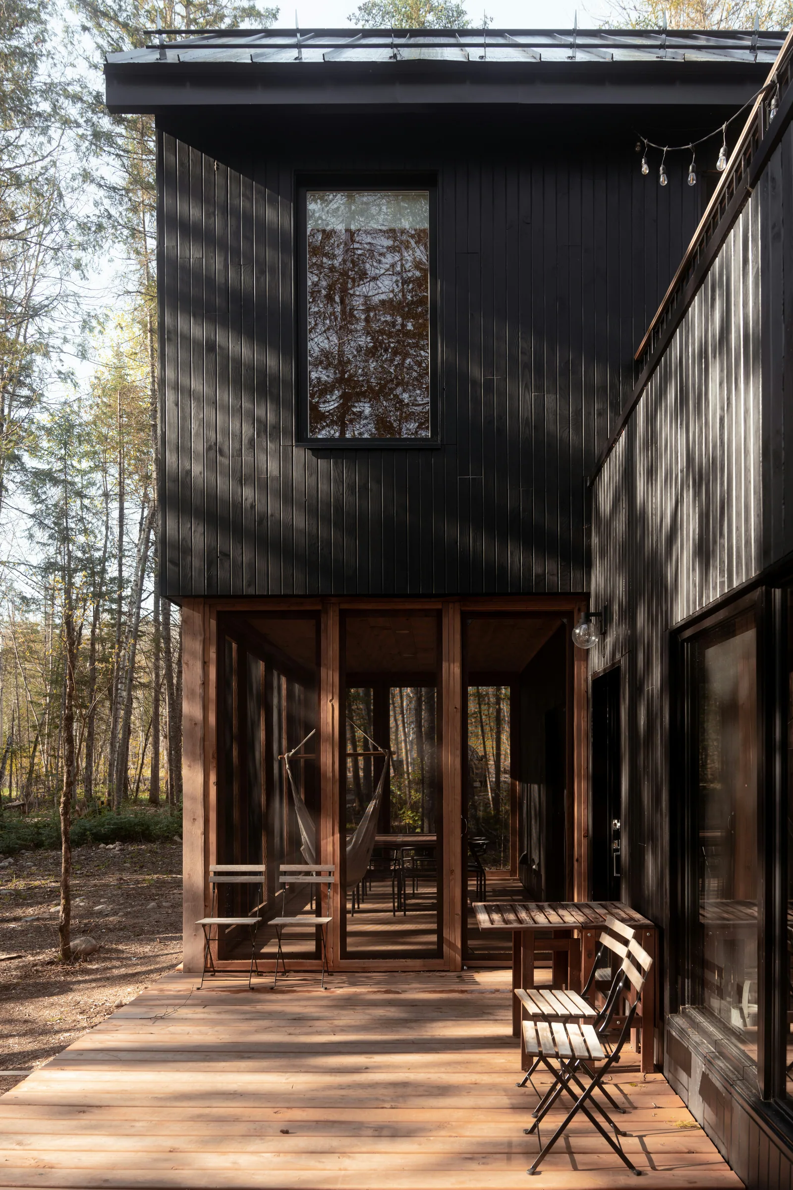 A black timber house with a deck, in the woods