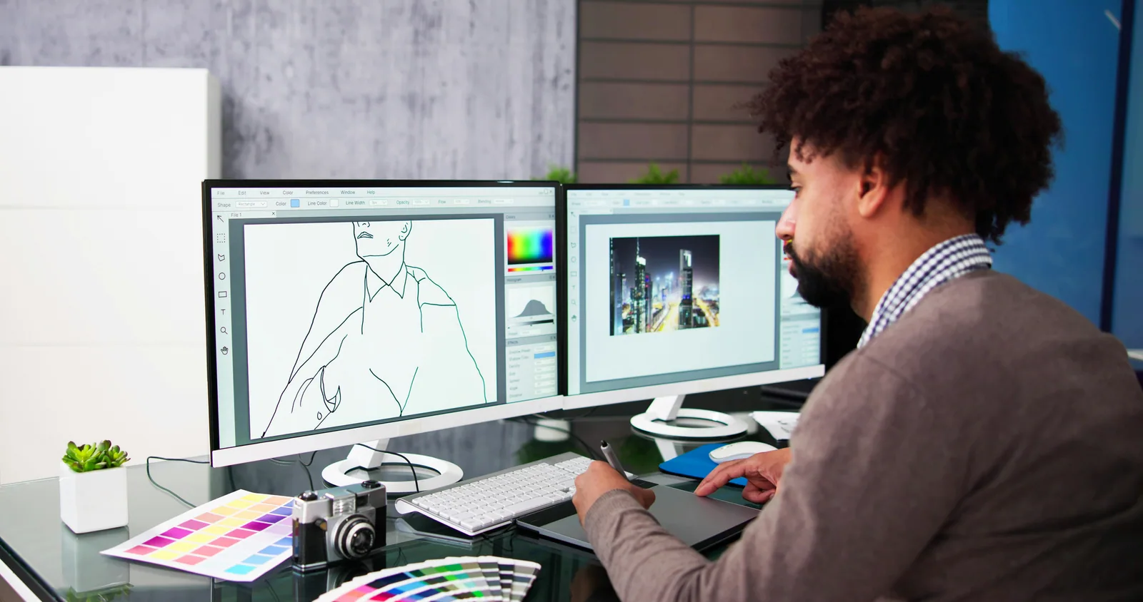 A designer at a desk with two screens and colour swatches