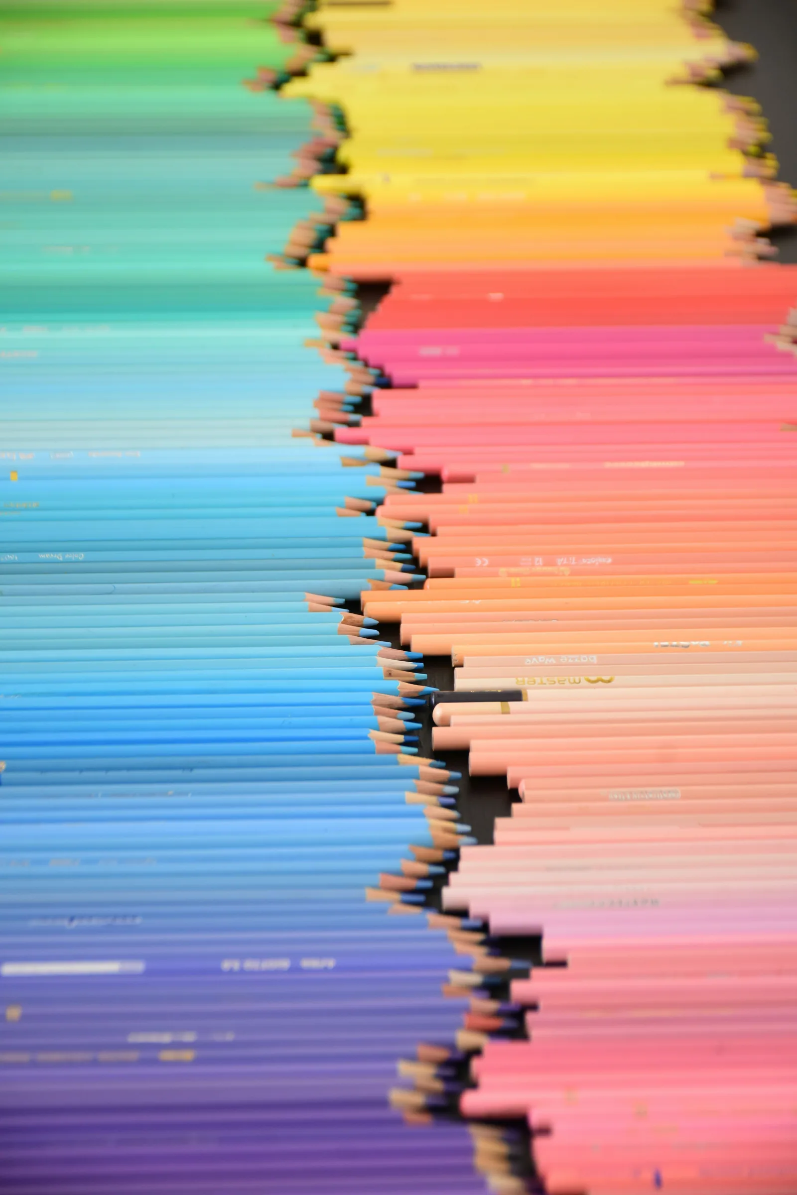 Coloured pencils lined up in a spectrum from blue to yellow