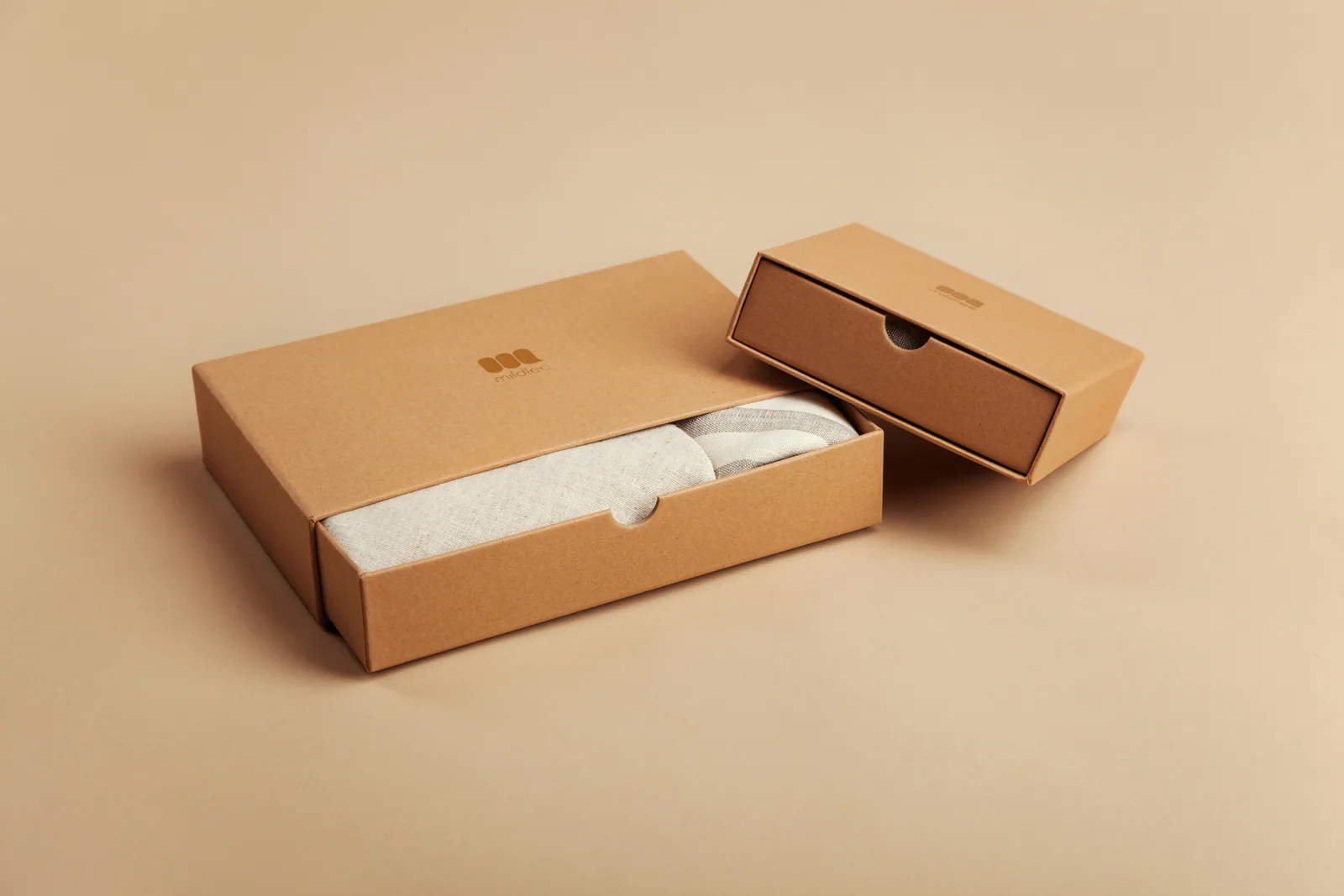 Plain kraft packaging boxes on a warm beige ground