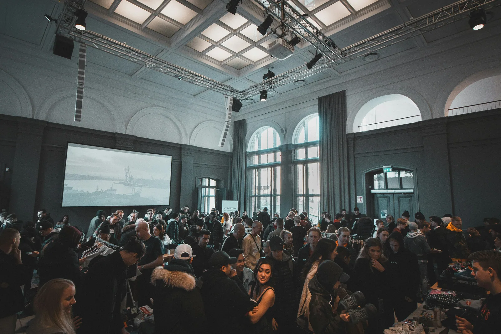 A full hall watching a talk on a big screen