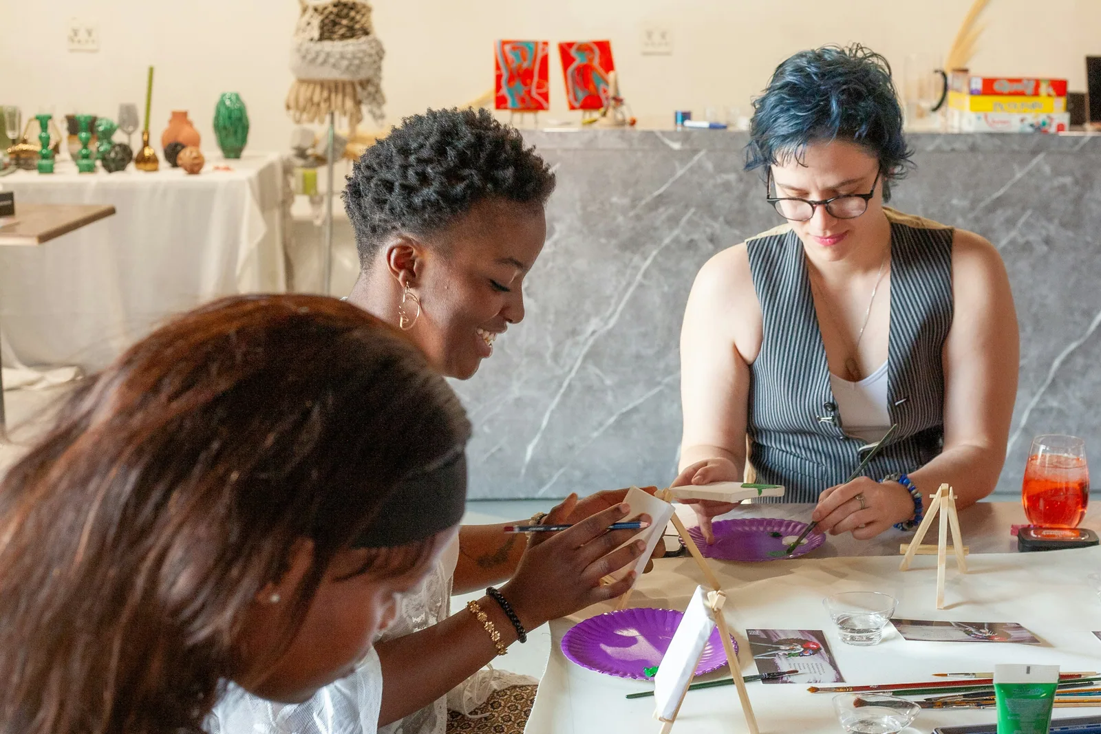 Three women painting and making things together at a table