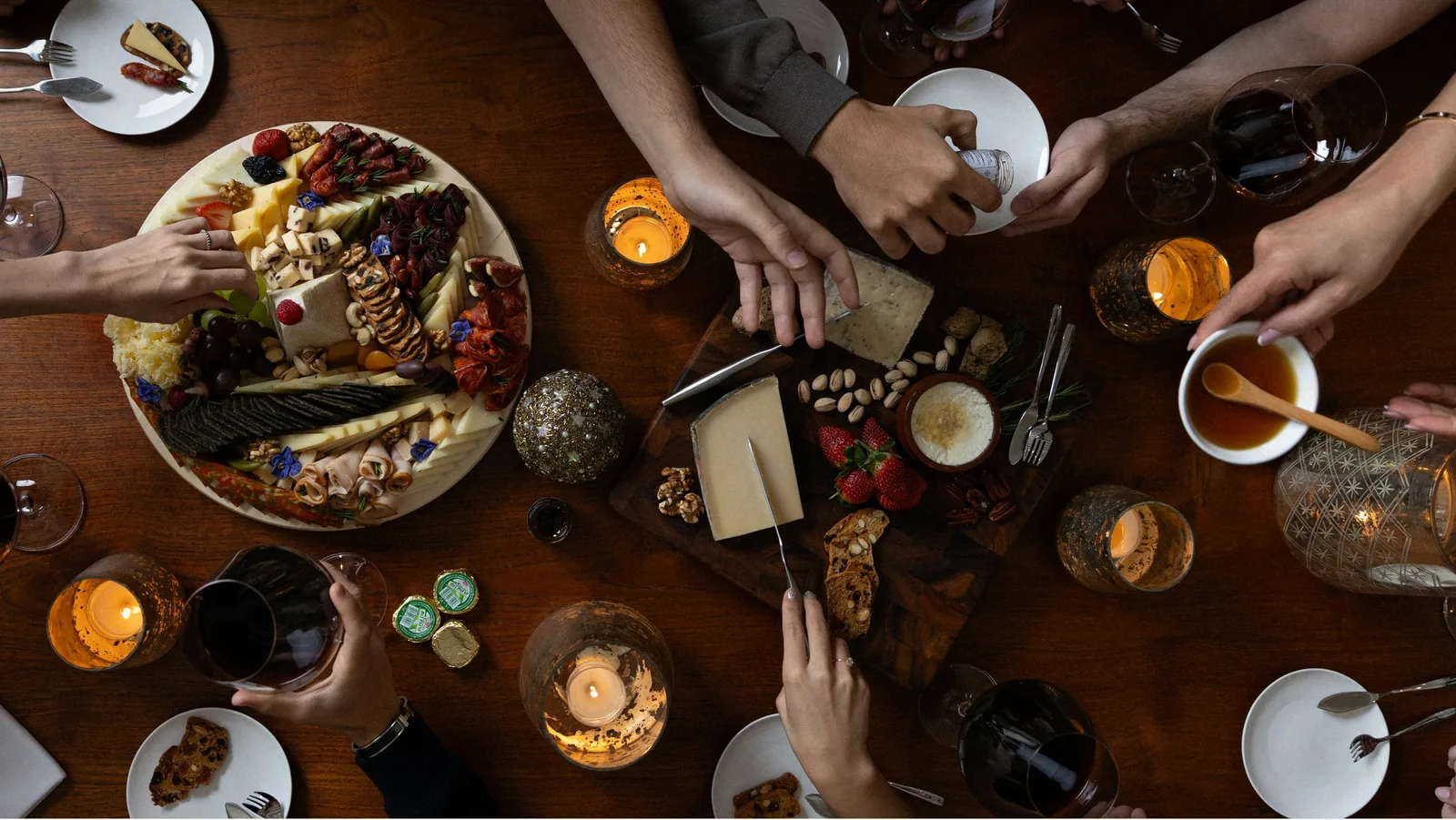 Hands reaching into a sharing board on a dark table, from above