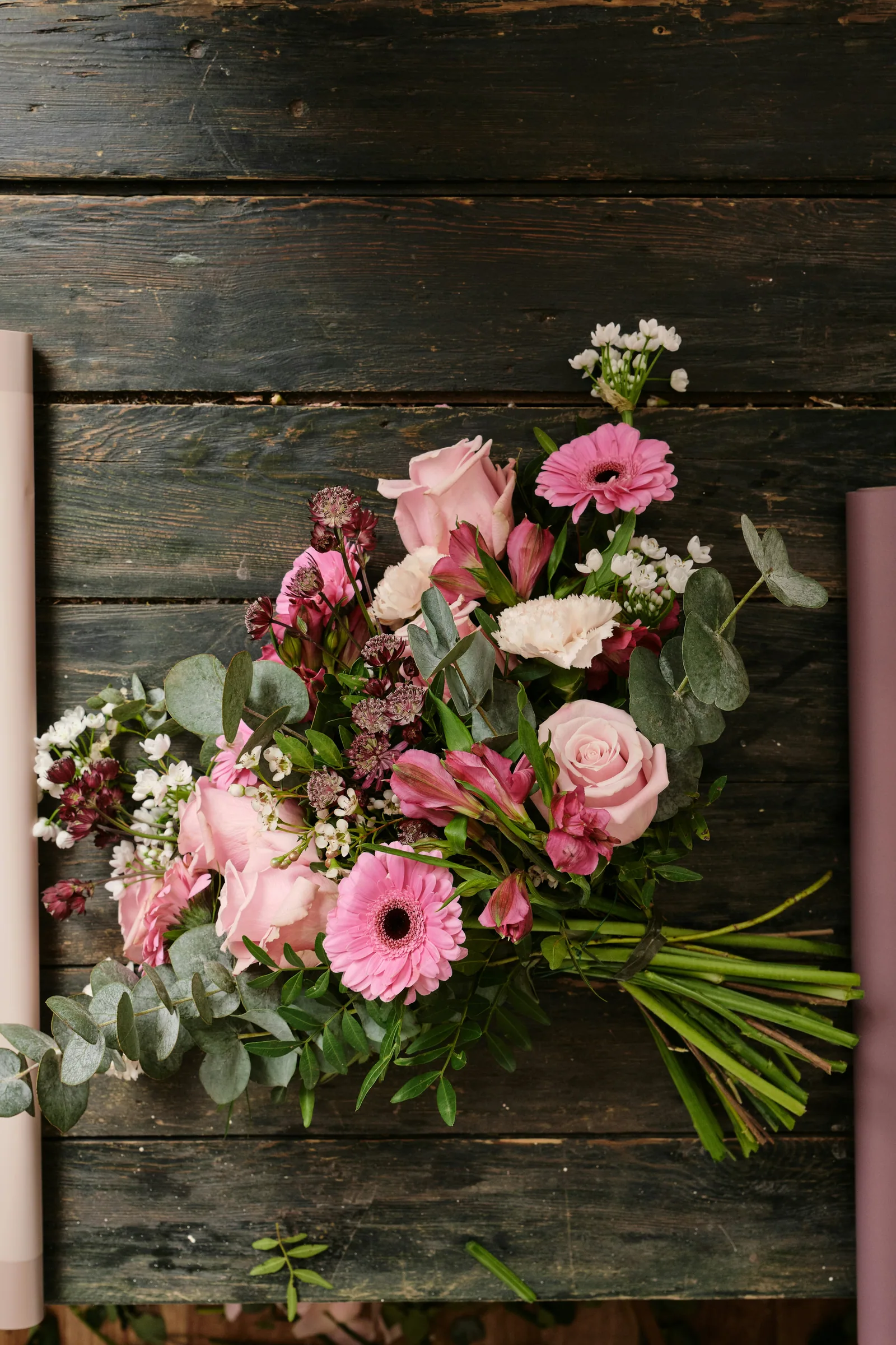 A pink bouquet laid on dark wood