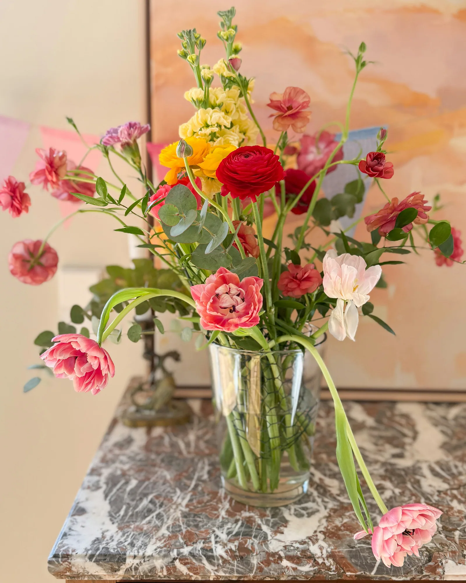A bright mixed arrangement in a glass vase on marble