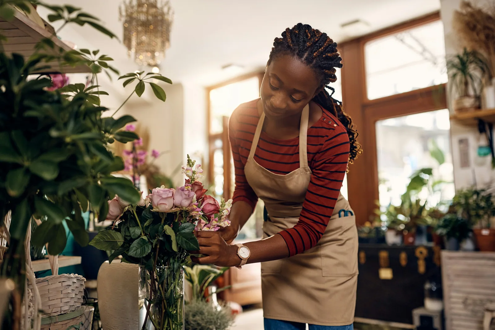 A florist in an apron arranging fresh flowers in her shop