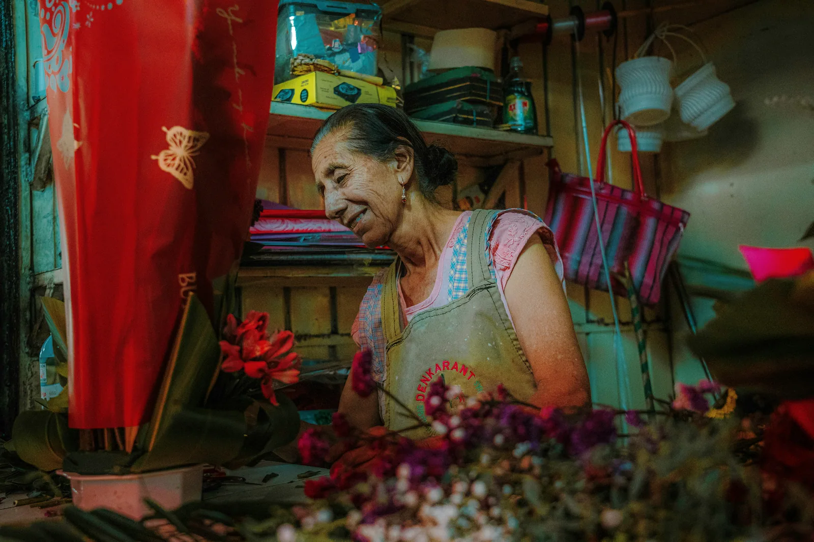A florist smiling as she works among buckets of flowers