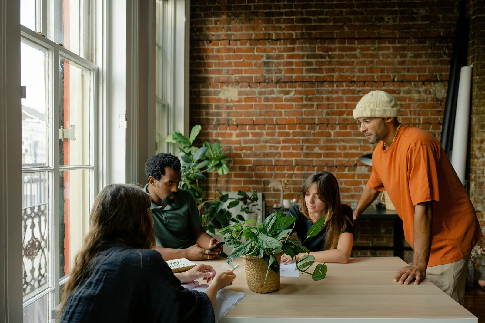 A small team round a table in a room with brick walls and plants