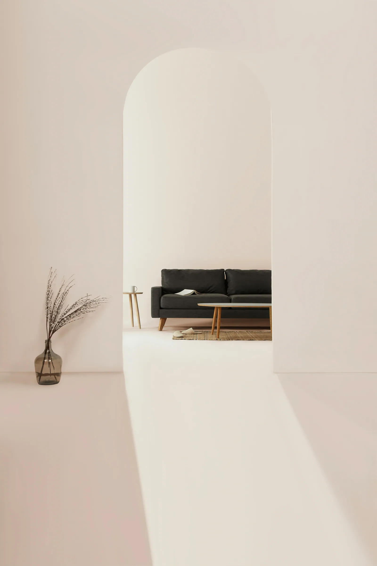 A plaster archway opening onto a black sofa in a pale room