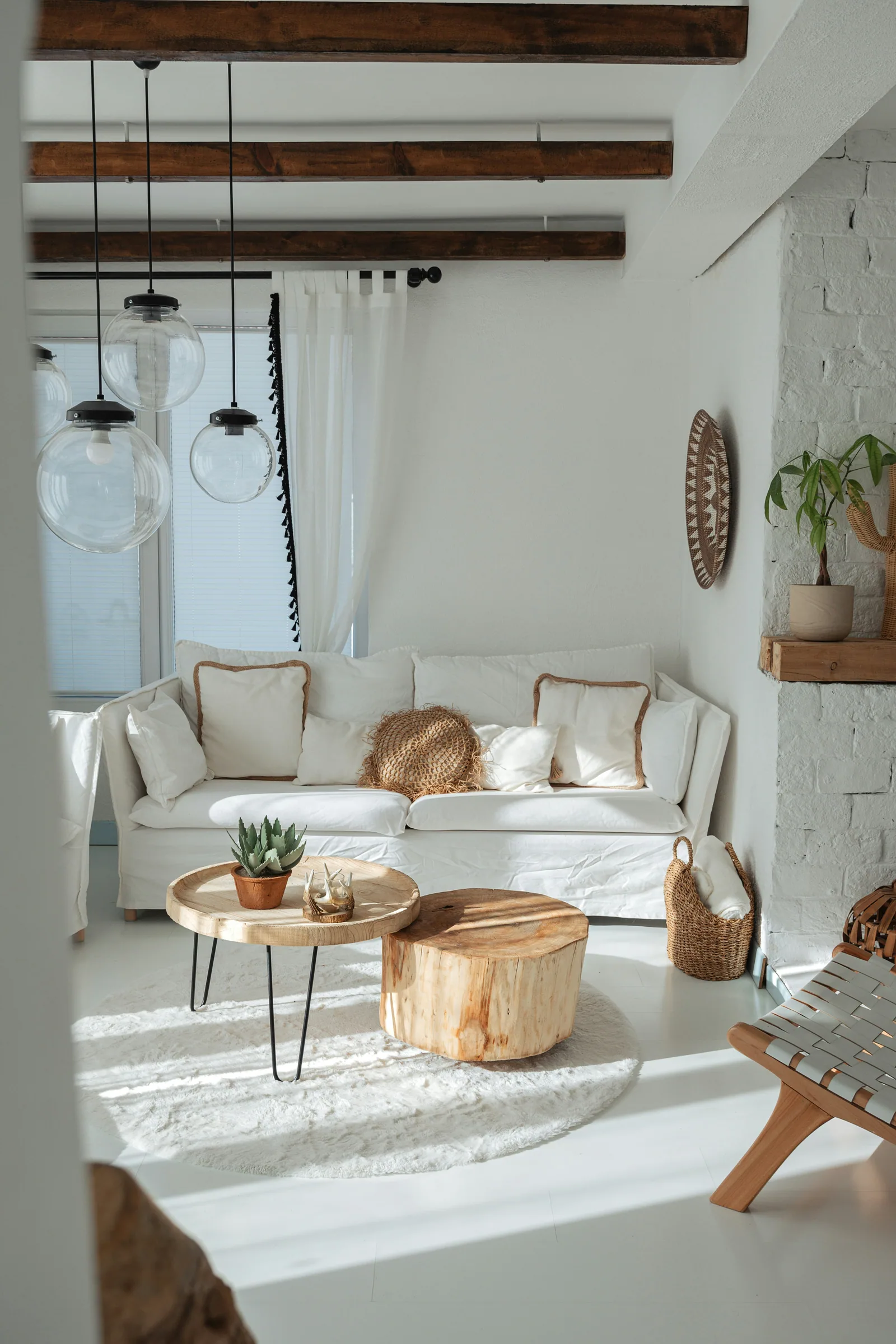 A white living room with wooden beams and glass globe pendants