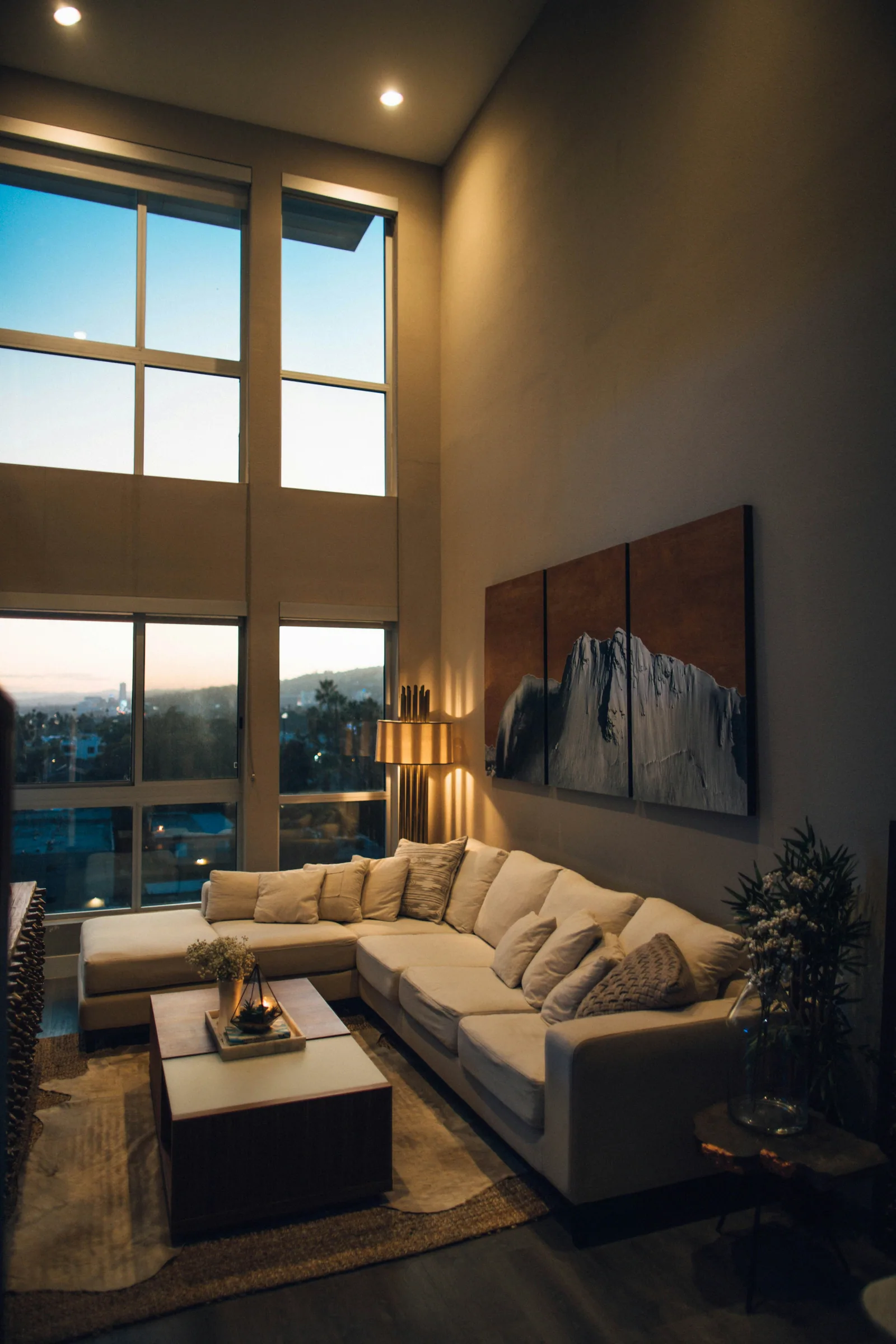 A tall living room at dusk with a large sectional sofa