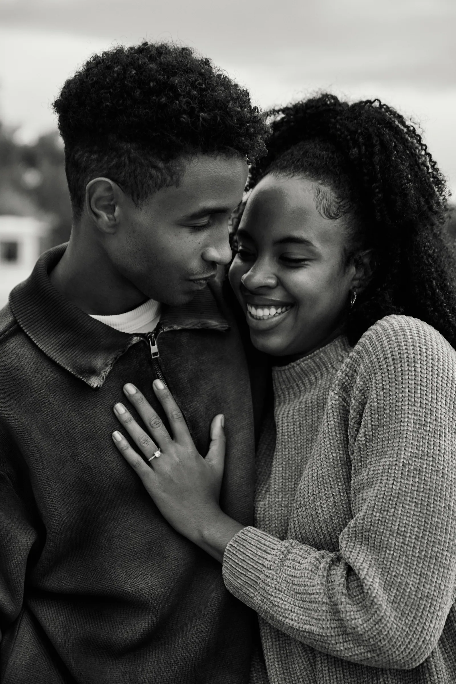 A black and white photo of a couple holding each other close, both smiling