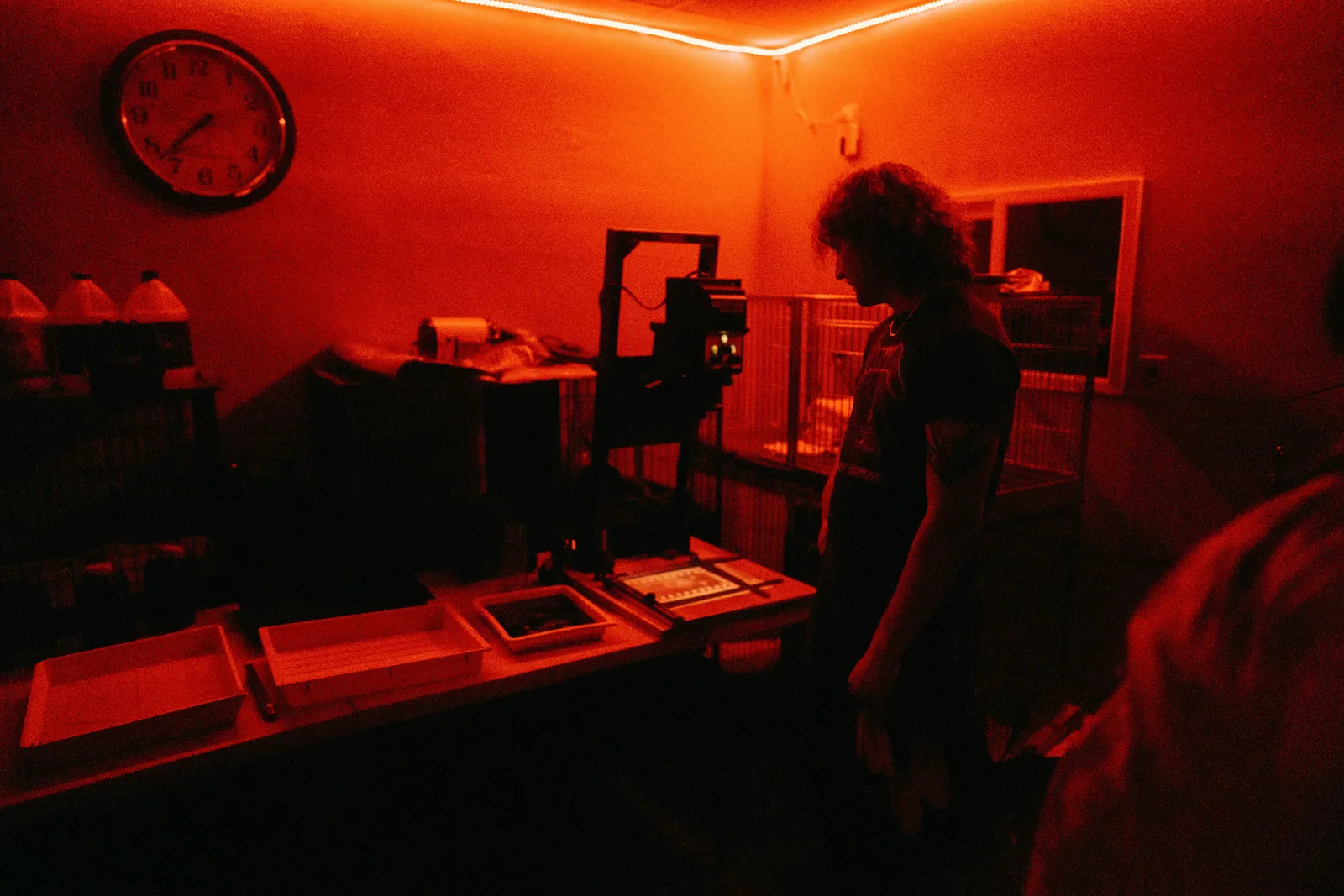 A darkroom in deep red light, with a woman at the bench