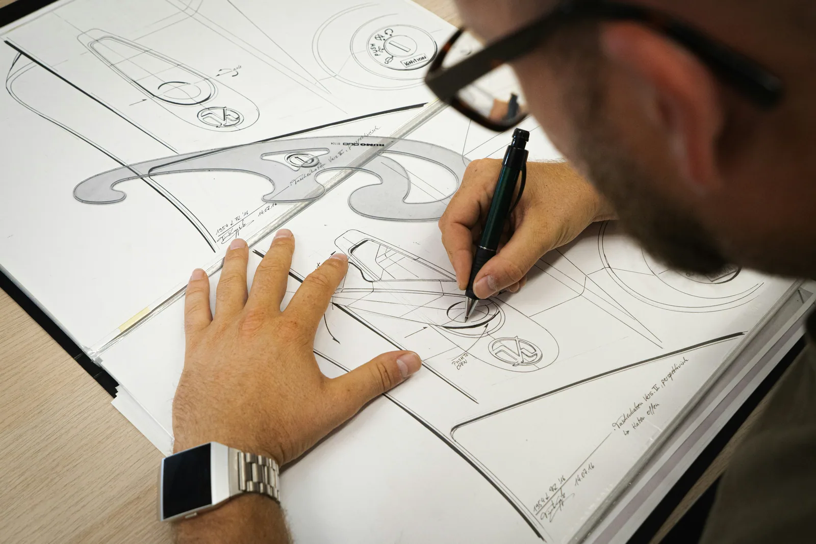 A man sketching a product drawing in a notebook
