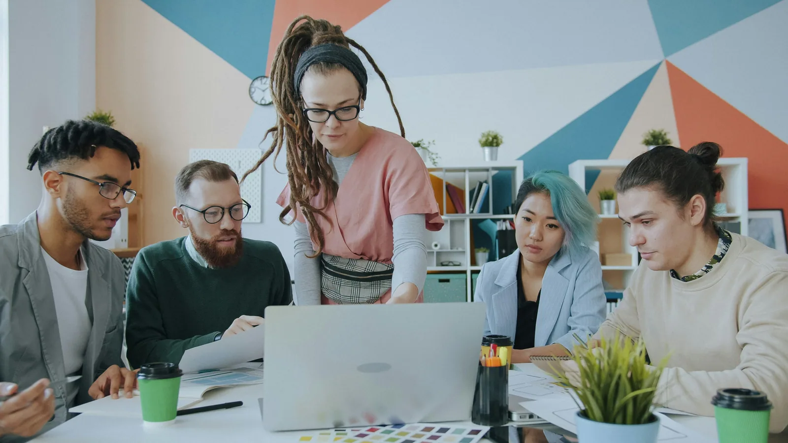 A mixed team gathered around a laptop in a bright studio