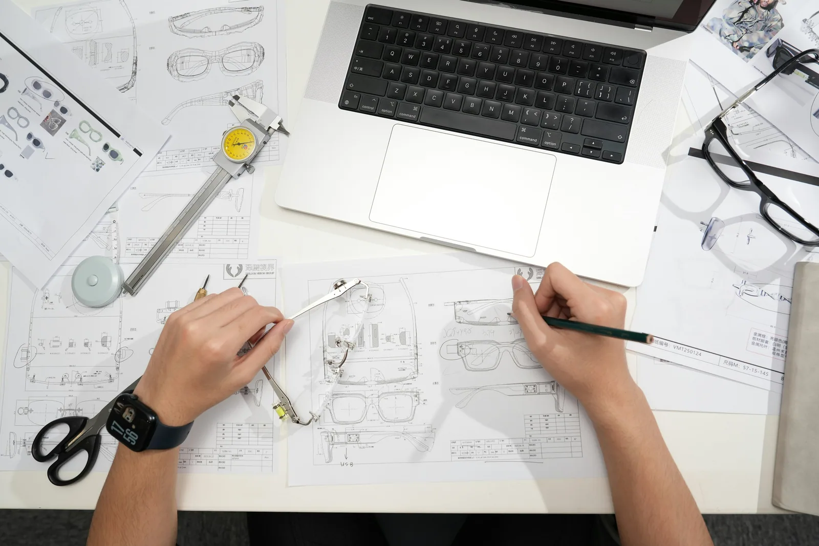 Drawings, measuring tools and a laptop on one desk