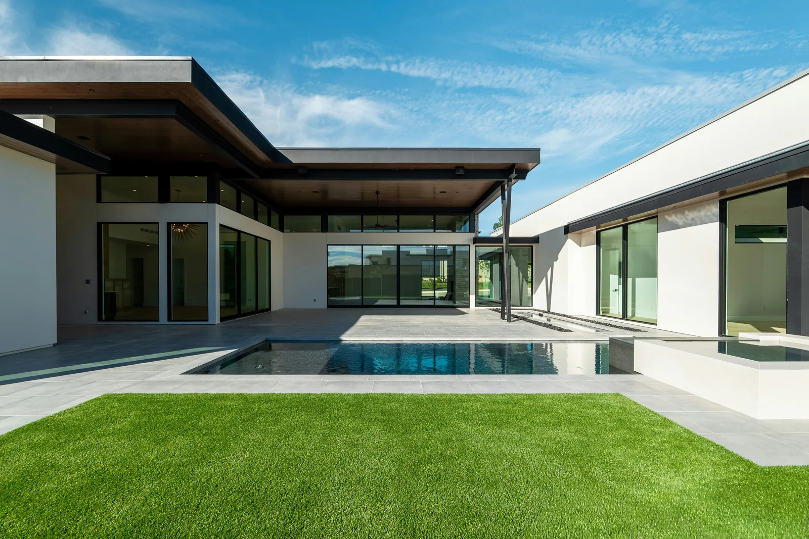 A single-storey modern house with a pool and a lawn