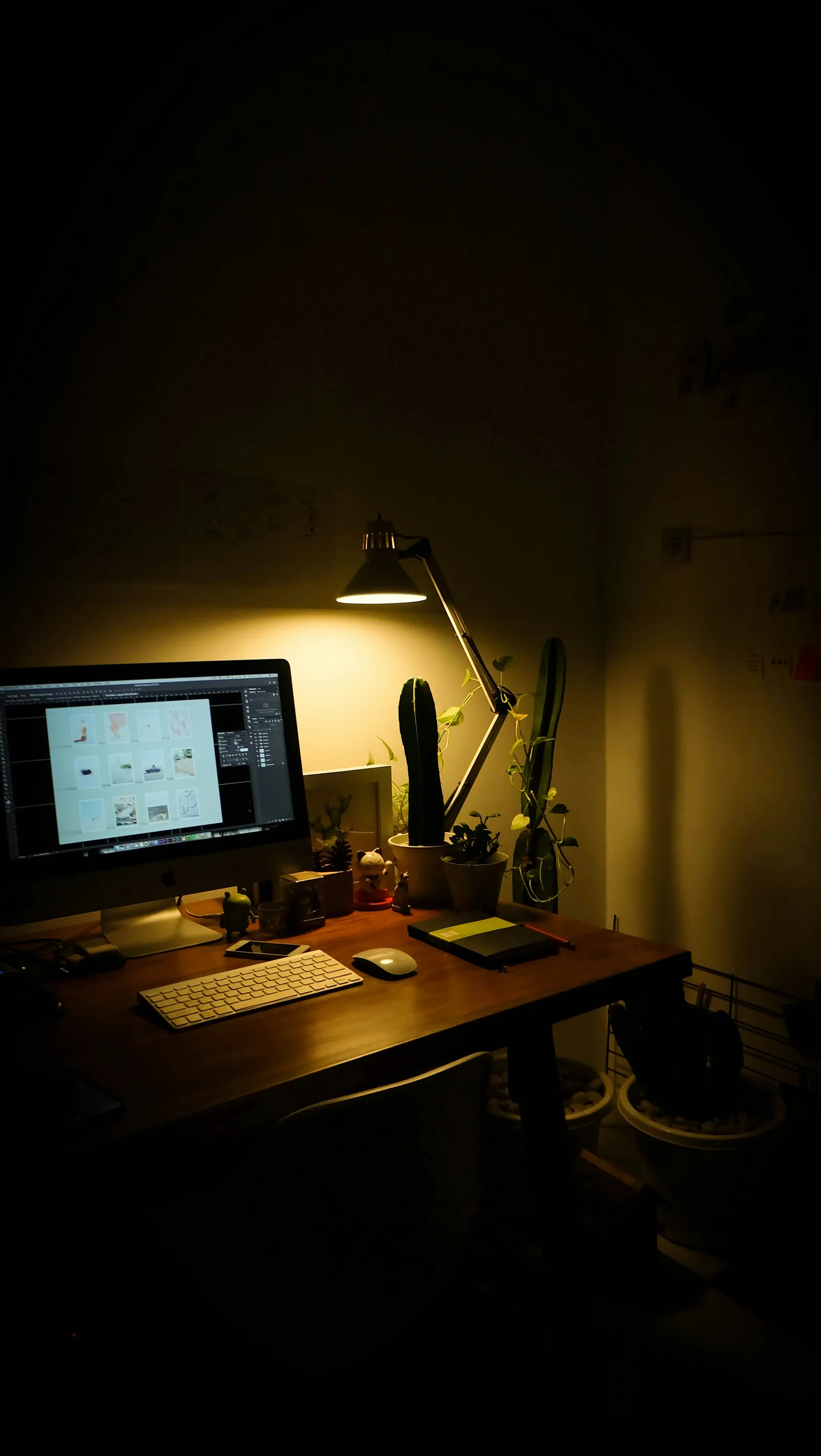 A dark desk lit by one lamp, a screen glowing
