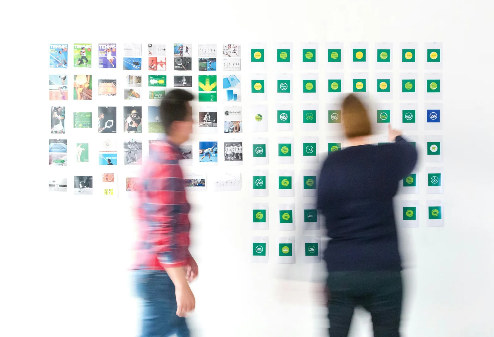 Two people looking over a wall of printed screens