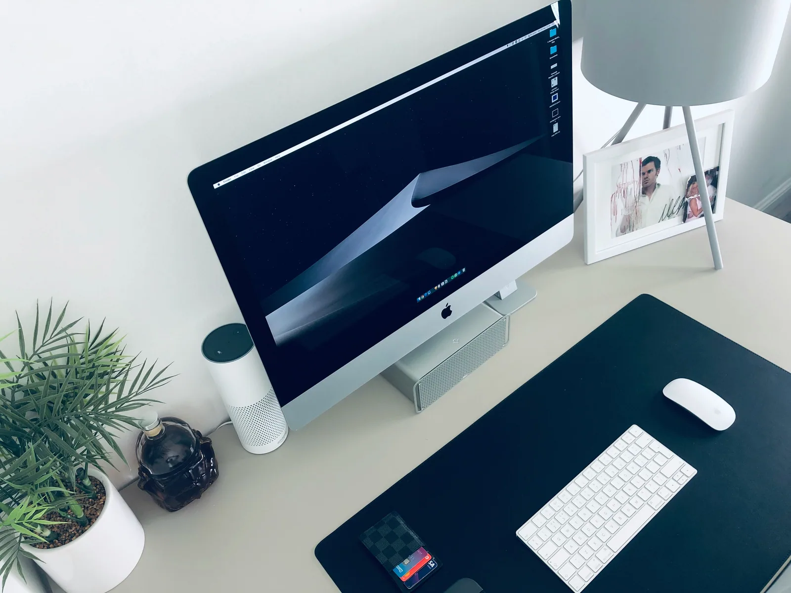 A clean white desk with a large screen and a plant