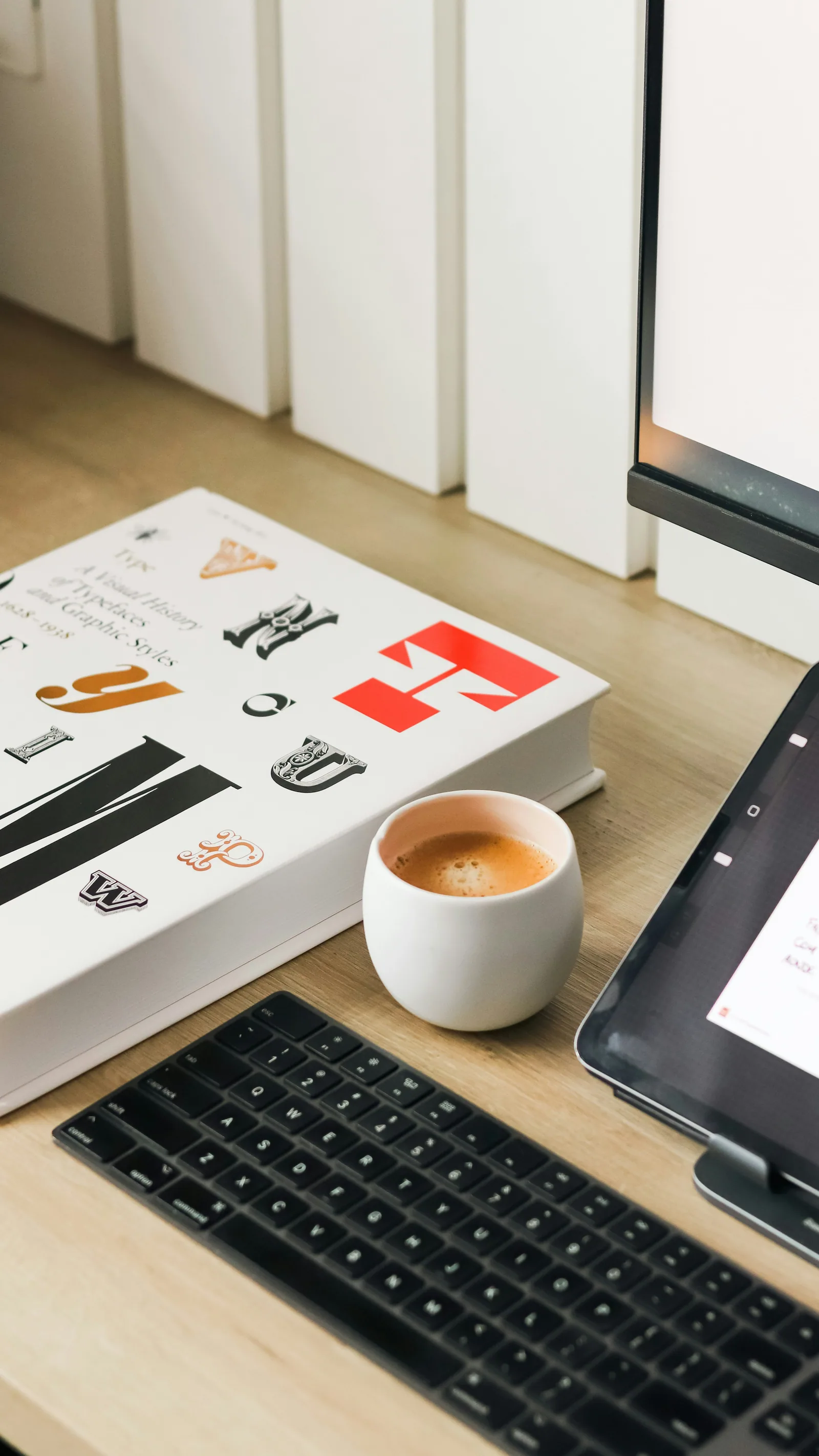 A desk with printed brand pages, a coffee and a keyboard