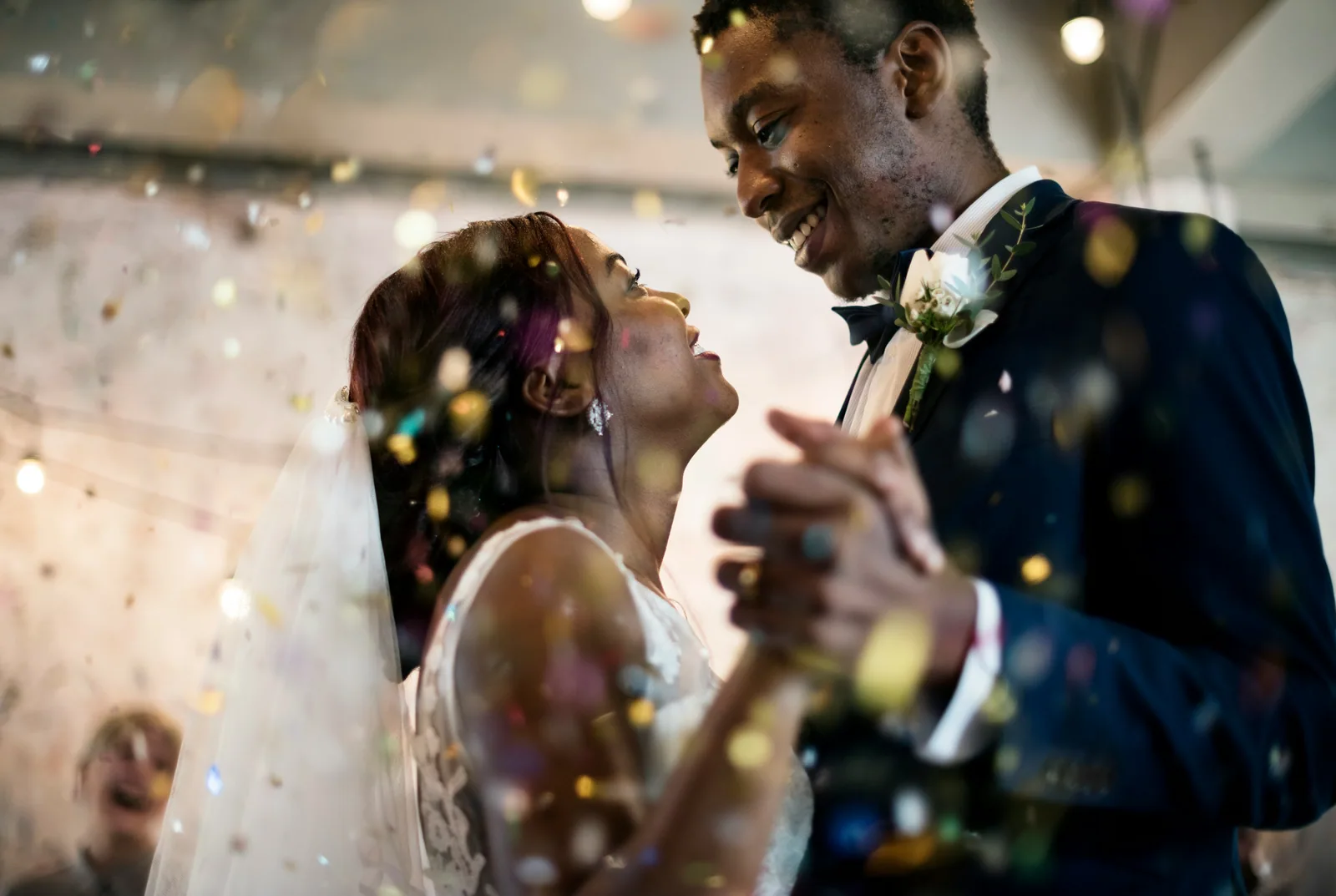 A couple dancing at their reception, confetti in the air