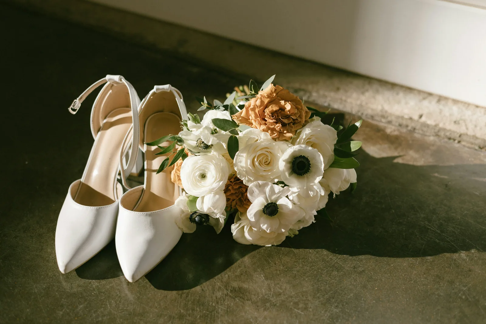White shoes beside a white and rust bouquet
